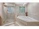 Bright bathroom featuring a glass shower and a soaking tub with tile surround and accent lighting at 2652 Lake Howell Ln, Winter Park, FL 32792