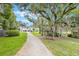 Well-manicured lawn with a stone pathway leading to a modern home surrounded by lush greenery and mature trees at 2652 Lake Howell Ln, Winter Park, FL 32792