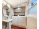 Well-lit laundry room with a pedestal sink and modern washer and dryer units at 2652 Lake Howell Ln, Winter Park, FL 32792