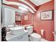 Stylish half-bathroom with red accent walls, a modern sink, and a decorative mirror at 2971 Cayman Way, Orlando, FL 32812