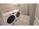 The laundry room has a washer and dryer set, grey tile floors, and a set of cabinets at 444 Halter Dr, Apopka, FL 32712