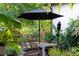 Outdoor dining area with a modern table and chairs surrounded by lush plants at 489 Grape Ave, St Cloud, FL 34769