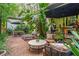 Brick patio with comfy seating, a round coffee table, mature landscaping, and lush tropical trees at 489 Grape Ave, St Cloud, FL 34769