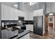 Well-lit kitchen featuring granite countertops, stainless steel appliances, and white cabinets, next to the hall entrance at 526 Sabal Trail Cir, Longwood, FL 32779