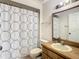 Well-lit bathroom featuring a wood-framed mirror, decorative shower curtain, and a white toilet at 5395 Vineland Rd # S, Orlando, FL 32811