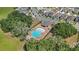 An aerial view of a community pool surrounded by a fence and mature trees with chairs and tables near the pool at 5639 Timber Meadow Way, St Cloud, FL 34771
