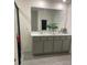 Bright bathroom with double vanity, large mirror, and gray cabinets offering modern elegance at 7172 Sw 135Th Pl, Ocala, FL 34473