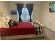 Bedroom features a comfortable bed with red comforter, large window, and a wall-mounted television at 7172 Sw 135Th Pl, Ocala, FL 34473