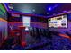 Exciting entertainment room featuring cinema-style seating, a big screen, neon lighting, and a vibrant, playful design at 884 Golden Bear Dr, Reunion, FL 34747