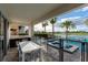 Charming covered patio with a dining table, outdoor kitchen, serene lake view, and tropical palms, ideal for al fresco dining at 884 Golden Bear Dr, Reunion, FL 34747