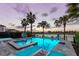 Sparkling pool featuring an attached spa, palm trees, playground amenity and comfortable deck chairs at 884 Golden Bear Dr, Reunion, FL 34747