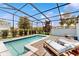 Sparkling pool with brick trim and lounge chairs in a screened-in patio enclosure at 8900 Sydney Ave, Kissimmee, FL 34747