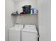 Bright laundry room features a white washer and dryer, complemented by overhead storage shelving at 914 Fallon Hills Dr, Haines City, FL 33844