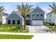 Beautiful two-story home featuring manicured landscaping, a palm tree, and a spacious three car garage at 9352 Santorini Dr, Orlando, FL 32827