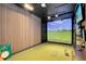 Bright golf simulator room with putting green, computer for swing analytics, and large projector at 9352 Santorini Dr, Orlando, FL 32827