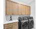 Well-equipped laundry room boasts modern washer and dryer, sleek cabinetry, and a stylish sink area, offering convenience and efficiency at 9352 Santorini Dr, Orlando, FL 32827