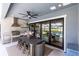 Covered outdoor kitchen with a gas grill, dining table and views of the sparkling pool at 9352 Santorini Dr, Orlando, FL 32827