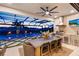 Screened outdoor kitchen and pool view at dusk with custom grill, TV and built in lighting at 9352 Santorini Dr, Orlando, FL 32827