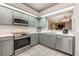 Modern kitchen with stainless steel appliances, gray cabinets, and a view to the living area at 1010 Leinhart Ct, Oviedo, FL 32765