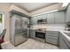 Well-lit kitchen with stainless steel appliances, gray cabinets, and marble countertops at 1010 Leinhart Ct, Oviedo, FL 32765