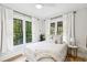 Bright bedroom features white walls, black trim windows with green views, and a comfortable white bed at 112 E Spruce St, Orlando, FL 32804
