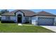 Charming one-story home featuring a gray roof, attached garage, and well-maintained front yard at 1930 Dolphin Drive, Kissimmee, FL 34759