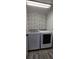 Modern laundry room with a gray front load washer and dryer and a black and white patterned wall at 1930 Dolphin Drive, Kissimmee, FL 34759
