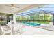 A covered patio features an outdoor kitchen, dining set, and lounge chairs next to the screened pool at 2496 Rama Dr, Kissimmee, FL 34746