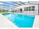 A luxurious screened-in pool with an outdoor dining area and serene view at 2496 Rama Dr, Kissimmee, FL 34746