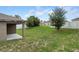 Expansive backyard with a covered patio, lush green lawn, mature trees, and a white fence at 257 Fig Ct, Kissimmee, FL 34759