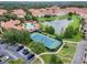 Beautiful aerial view of a community with a pool, tennis court, and lake with fountain, surrounded by lush greenery at 2704 Lobelia Dr, Lake Mary, FL 32746