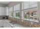 Gourmet kitchen showcasing granite counters, stylish tile backsplash, and bright light from multiple windows at 2704 Lobelia Dr, Lake Mary, FL 32746