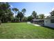 This backyard has green grass, a screened in pool, mature trees, and is surrounded by a wooden fence at 300 Royal Palm Ct, Longwood, FL 32779