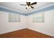 This bedroom features wood floors, two windows, a ceiling fan, and white trim at 300 Royal Palm Ct, Longwood, FL 32779
