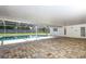 A covered patio, an exterior door, and a large pool with a brick surround highlight the outdoor living in this backyard at 300 Royal Palm Ct, Longwood, FL 32779