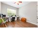 A modern office features a window view, wood flooring, desk setup with dual monitors, and a wooden storage chest at 3753 Heirloom Rose Pl, Oviedo, FL 32766