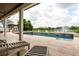 Covered patio overlooking a pristine pool and backyard with serene views of a lake and fountain at 4221 Isle Vista Ave, Belle Isle, FL 32812