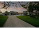Attractive home exterior showcasing a circular driveway, verdant lawn, and subtle outdoor lighting highlighting its architectural details at 49 Interlaken Rd, Orlando, FL 32804