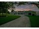 Charming home exterior showcasing a curved driveway, lush green lawn, and a serene atmosphere under the evening sky at 49 Interlaken Rd, Orlando, FL 32804