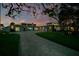 Elegant home exterior at twilight featuring a long driveway, manicured lawn, and tasteful lighting enhancing its curb appeal at 49 Interlaken Rd, Orlando, FL 32804
