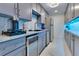 Compact kitchenette features stainless steel appliances, modern gray cabinets, and granite countertops with tile backsplash at 49 Interlaken Rd, Orlando, FL 32804