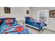 Bright bedroom features 2 twin beds with comic book themed linens and white walls at 4984 Windermere Ave, Kissimmee, FL 34746