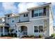 Charming townhome showcasing a well-maintained lawn, neutral gray exterior, shutters, and covered porch with the U.S. flag at 4984 Windermere Ave, Kissimmee, FL 34746