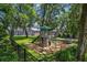 Backyard playground with a tower, slide, swing, and mature shade trees in a fenced yard at 672 Seven Oaks Blvd, Winter Springs, FL 32708