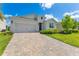 Charming single-Gathering home with a two-car garage, brick driveway, manicured lawn, and tasteful landscaping at 744 Curly Locks Loop, Apopka, FL 32703