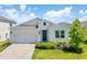 Charming single-story home featuring a manicured lawn, brick driveway and a classic blue front door with wreath at 744 Curly Locks Loop, Apopka, FL 32703