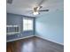 Blue accent wall, ceiling fan, built-in desk, window with blinds, and dark hardwood floors at 831 Corvina Dr, Davenport, FL 33897