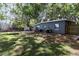 Backyard with a modern building, green lawn, shade trees, patio seating, and a trampoline at 845 Edgewater Cir, Eustis, FL 32726