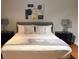 Stylized bedroom featuring hardwood floors, queen-sized bed with decorative pillows, dark wood nightstands, and modern wall art at 8894 Candy Palm Rd, Kissimmee, FL 34747