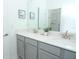 Bright bathroom featuring a double vanity with gray cabinets, modern fixtures, and decorative art at 976 Leader St, Davenport, FL 33896
